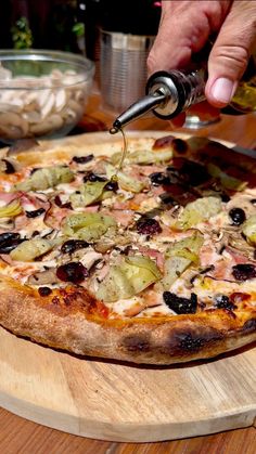 a person is cutting into a pizza with olives and other toppings on it