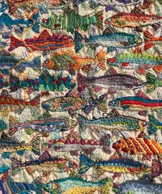 an image of colorful fish in the ocean on a white cloth textured with multicolored threads