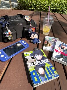 a table topped with books and toys next to a cell phone on top of a wooden table