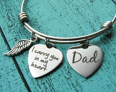 two heart shaped charms are attached to a bangle bracelet that says, mom and dad