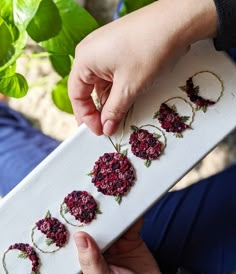 a person is holding a white board with flowers on it and threading them together