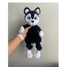 a hand holding a small black and white stuffed animal