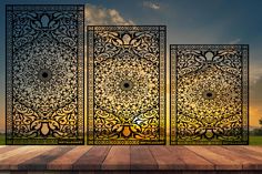 three metal screens sitting on top of a wooden platform in front of a sunset sky