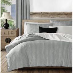 a bed with white and brown striped comforter next to a wooden headboard in a bedroom