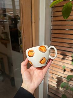 a hand holding a coffee cup with oranges on it