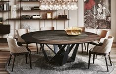 a round table with chairs around it in front of a book shelf and chandelier