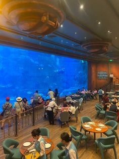 people sitting at tables in front of an aquarium