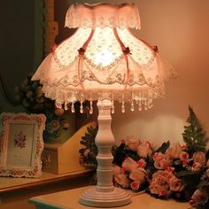 a white lamp sitting on top of a table next to flowers and a mirror in a room