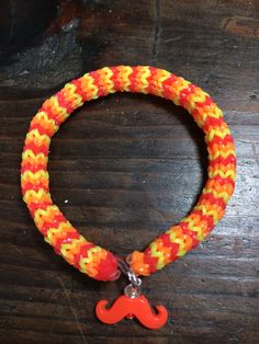 an orange, yellow and red bracelet with a moustache charm hanging from it