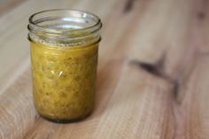 a jar filled with mustard sitting on top of a wooden table