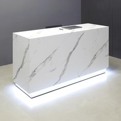 a white marble counter with a cell phone on it's display stand in front of a gray wall