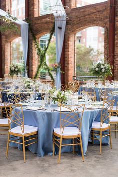 the tables are set with blue linens and gold chairs for an elegant wedding reception