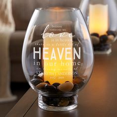 a glass vase filled with rocks on top of a wooden table next to a candle