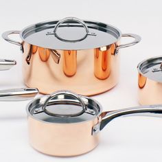 an assortment of pots and pans on a white surface with the lids down,