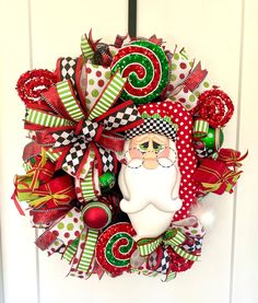 a christmas wreath on the front door with santa's face and red green and white ribbons