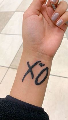 a woman's wrist tattoo with the word xo on it