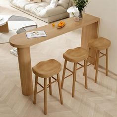 three stools sit at the end of a table in front of a couch and coffee table