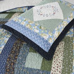 a quilted bedspread with blue, green and white flowers on the edges