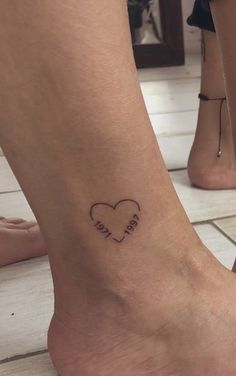 a woman's foot with a heart tattoo on it