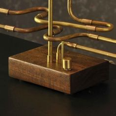 a wooden stand with brass colored metal pipes on it's sides and a black surface