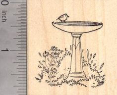 a rubber stamp with a bird sitting on a pedestal in front of bushes and flowers