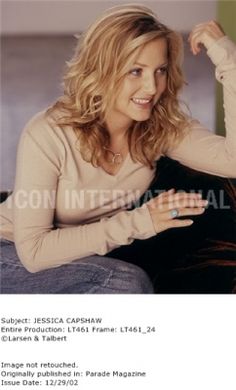 a woman sitting on top of a couch with her arm in the air and smiling