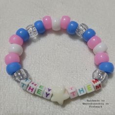 a pink, white and blue beaded bracelet with the word hey written on it