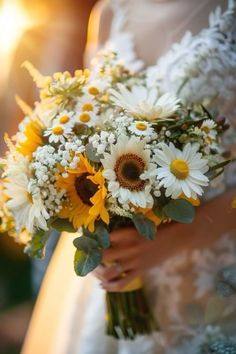 a bride holding a bouquet of sunflowers and daisies