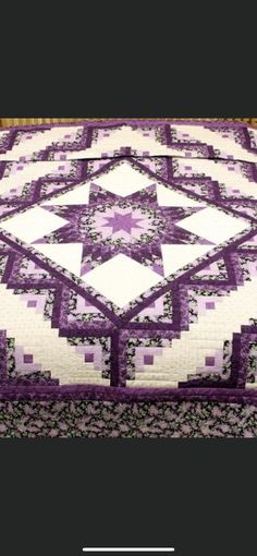 a purple and white quilt is on display