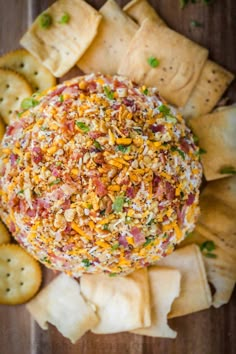 a cheese ball with crackers around it on a wooden table next to crackers