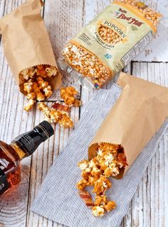 two bags filled with popcorn sitting on top of a table next to a bottle of beer