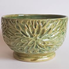 a green ceramic bowl sitting on top of a white table