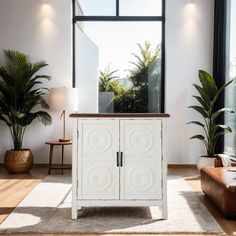 a white cabinet sitting in front of a window with potted plants next to it