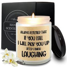 a candle that is sitting in front of a box with a flower on the side