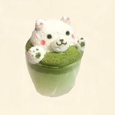 there is a small white bear on top of a green cup