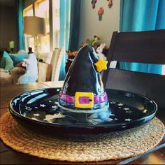 a black plate with a purple and yellow witches hat on it sitting on top of a wooden table