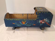 an old wooden box with painted designs on the sides and bottom, sitting on a white surface