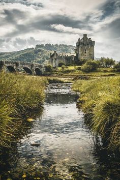 a river running through a lush green field next to a castle