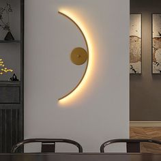 a table and chairs in front of a white wall with a crescent shaped light on it