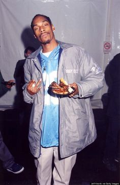 a man standing in front of a white wall holding food