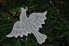 an ornament hanging from a christmas tree with white lace on it's wings