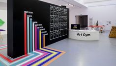 an art gallery with various colored lines on the floor and tables in front of it