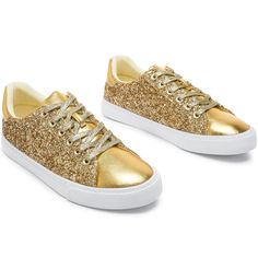 a pair of gold sneakers with white soles and glitter detailing on the upper part