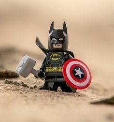 a lego batman with a captain america shield on it's chest, standing in the sand