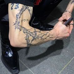 a person with tattoos on their legs holding a cell phone