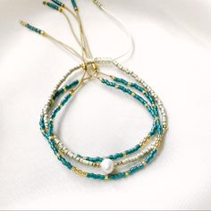 three stranded bracelets with pearls and blue glass beads on a white tablecloth