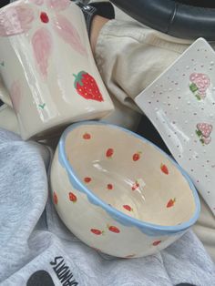 bowls and plates are sitting on the floor next to each other, including one with strawberries painted on it