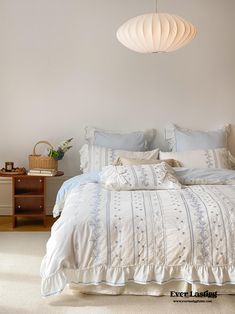 a bed with white sheets and pillows in a bedroom next to a lamp hanging from the ceiling