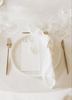 a white table setting with silverware and napkins