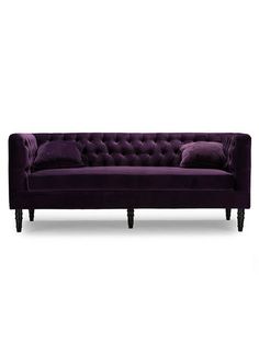 a purple velvet couch with two pillows on it's back and one arm extended